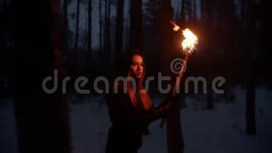 年轻的迷路女子带着<strong>火把</strong>在冬天的森林里走着，晚上寻找出路